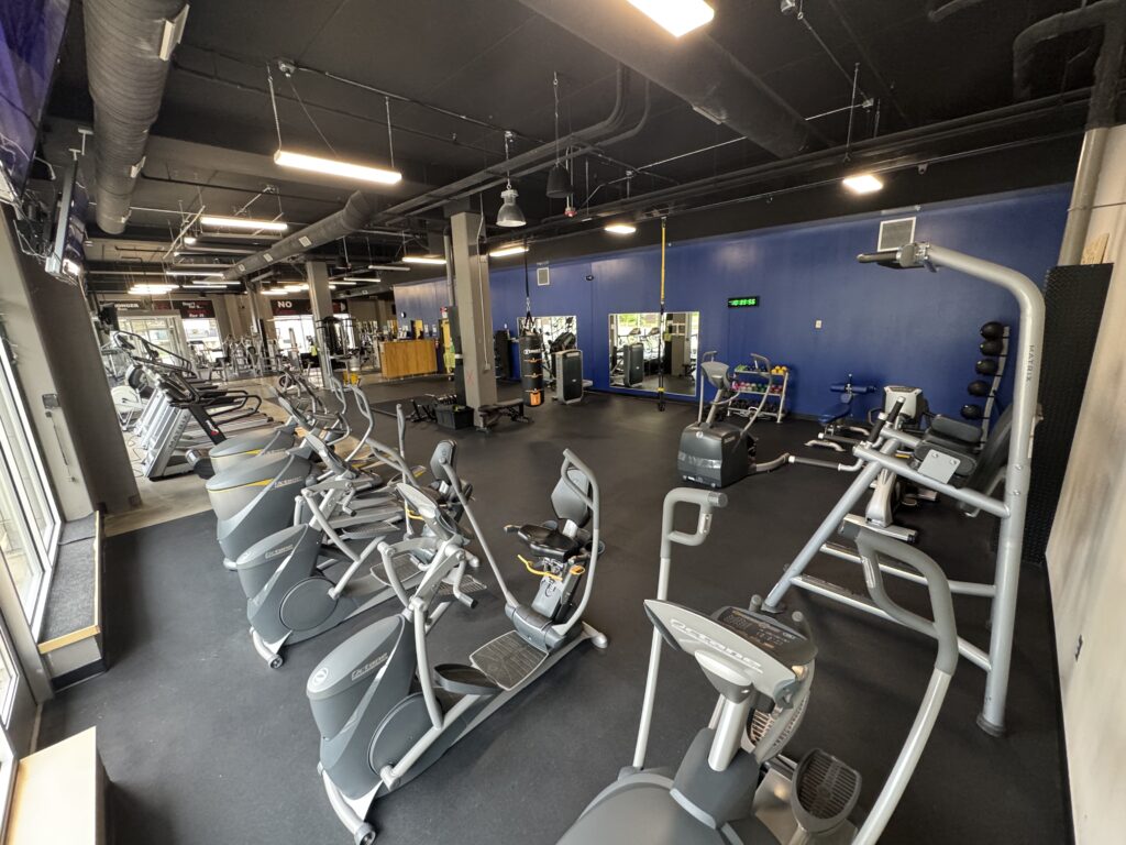 Treadmills, Bikes, Elliptical Machines, Stair Steppers, and Row Machine with TVs at Fifth Street Fitness Gym in Coralville, Iowa. (zoomed out)